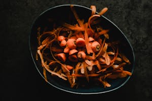 Carrot peels and scraps in a dark bowl.